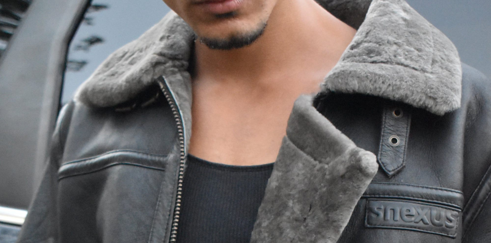 Person wearing a gray shearling jacket with a blurred background
